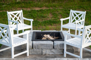 White chairs sitting around a square retaining wall fire pit